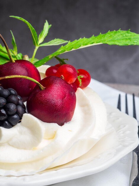 Tort bezowy pavlova ze świeżą truskawką jeżynową na betonowym tle