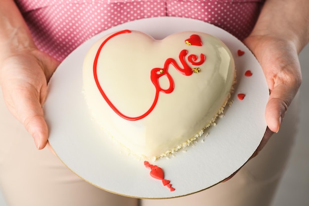 Zdjęcie tort musowy w kształcie serca z napisem love w rękach dziewczynki na walentynki i 14 lutego