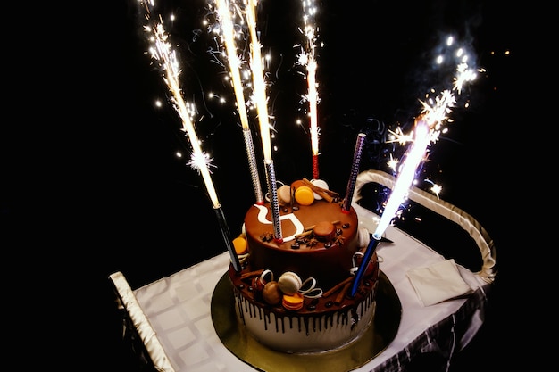 Tort urodzinowy z fajerwerkami na stole w czarnej powierzchni