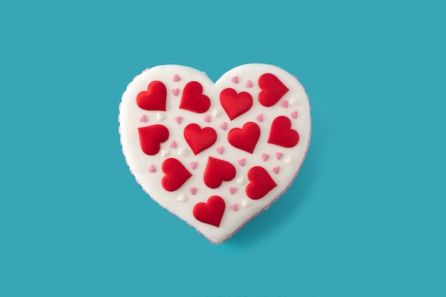Tort w kształcie serca na Walentynki, ozdobiony cukrowymi serduszkami na niebieskiej powierzchni