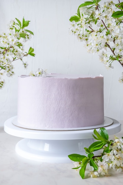 Tort weselny różowy tort na stojaku wśród gałęzi kwitnących wiśni.
