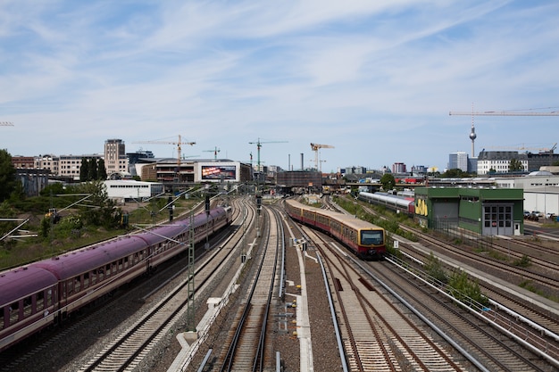 Tory kolejowe z pociągiem i S-Bahn z panoramą miasta i wieżą telewizyjną w Berlinie