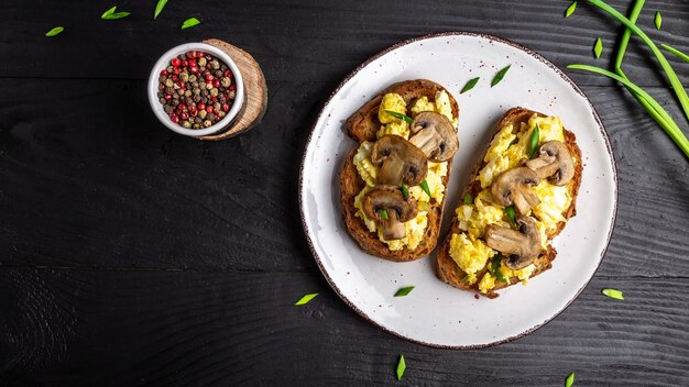 Tost pełnoziarnisty z jajecznicą z pieczarkami i twarogiem. zdrowe śniadanie lub brunch. miejsce na tekst, widok z góry.