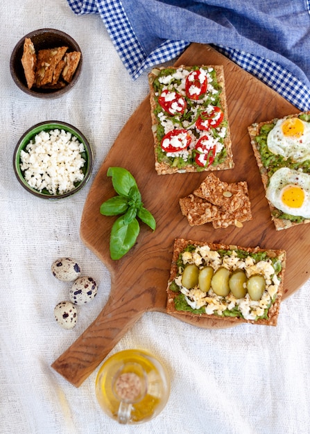 Tost Z Awokado Z Pomidorkami Koktajlowymi, Serami Greckimi, Jajkami Sadzonymi, Ogórkiem I Gałązką Bazylii.