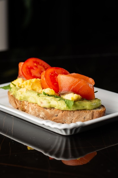 Tost z chleba gryczanego z jajkiem pokrojone awokado łosoś pomidory i sałata Menu dietetyczne Leżący płasko