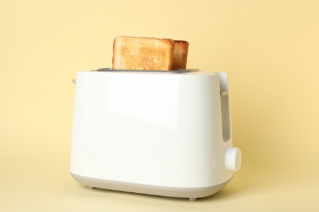 Zdjęcie toster z kromkami chleba na beżu, z bliska