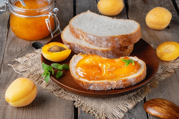 Tosty z chleba z konfiturą morelową i świeżymi owocami z miętą na starym drewnianym stole Smaczne śniadanie