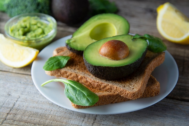 Tosty z guacamole, plasterki awokado. Zdrowa żywność, przekąska. Śniadanie. Drewniany stół rustykalny.