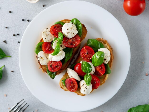 Tosty z serem mozzarella, pomidorami i liśćmi bazylii na jasnym tle Włoskie jedzenie Widok z góry
