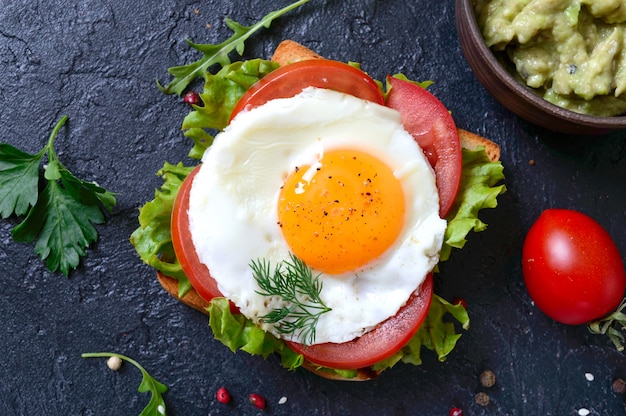 Tosty żytnie Z Puree Z Awokado, Jajkiem Sadzonym, świeżym Pomidorem, Ziołami. Smaczne śniadanie. Odpowiednie Odżywianie. Kanapka Z Jajkiem.