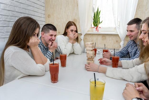 Towarzystwo przyjaciół pije sok i gra w wieżyczkę w kawiarni