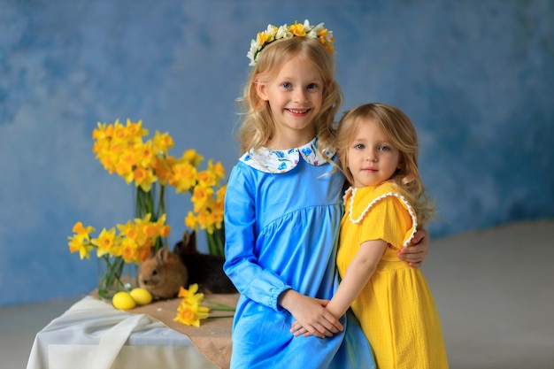 Tradycje wielkanocne 2 piękne dziewczyny w jasnych sukienkach trzymają w rękach króliki i kurczaki kartka wielkanocna