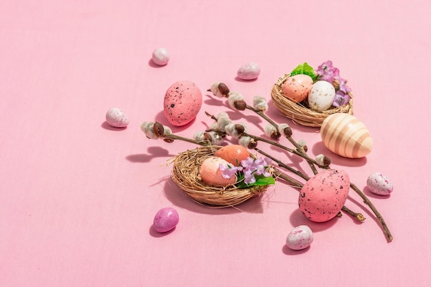 Tradycyjna kompozycja wielkanocna jaja ptasie gniazda gałązki wierzby tematyczne dekoracje różowe tło