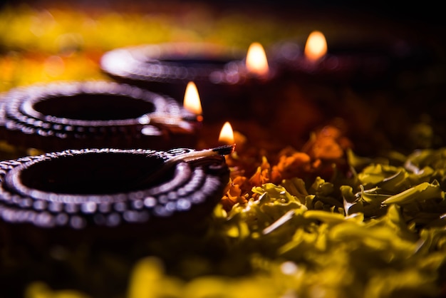 Zdjęcie tradycyjna lampa diya lub oliwna zapalona na kolorowym rangoli złożonym z płatka kwiatu, na festiwalu świateł zwanym diwali lub deepawali, selektywne ogniskowanie