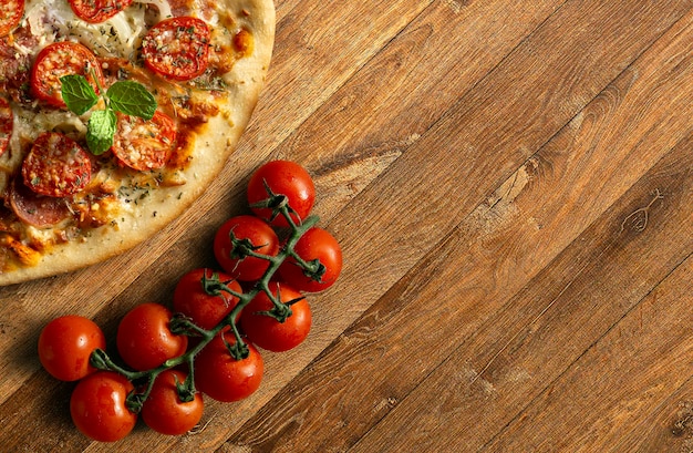 Tradycyjna pizza pepperoni z kiścią pomidorów na drewnianej podstawie Widok z góry