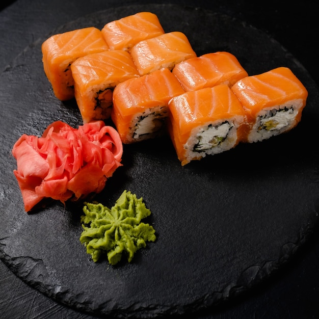 Tradycyjna przyprawa do sushi marynowany imbir i wasabi. Japońskie jedzenie. Roladki z krewetkami na ciemnym tle