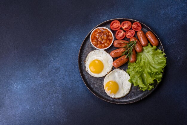 Tradycyjne angielskie śniadanie z jajkiem, grzankami, fasolkami, przyprawami i ziołami na szarym ceramicznym talerzu