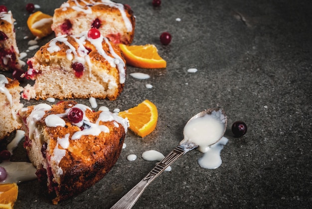 Zdjęcie tradycyjne brytyjskie angielskie wypieki. ciastka ciastka żurawina scones ze skórką pomarańczową, ze słodkim białym szkliwem, stół z czarnego kamienia, miejsce