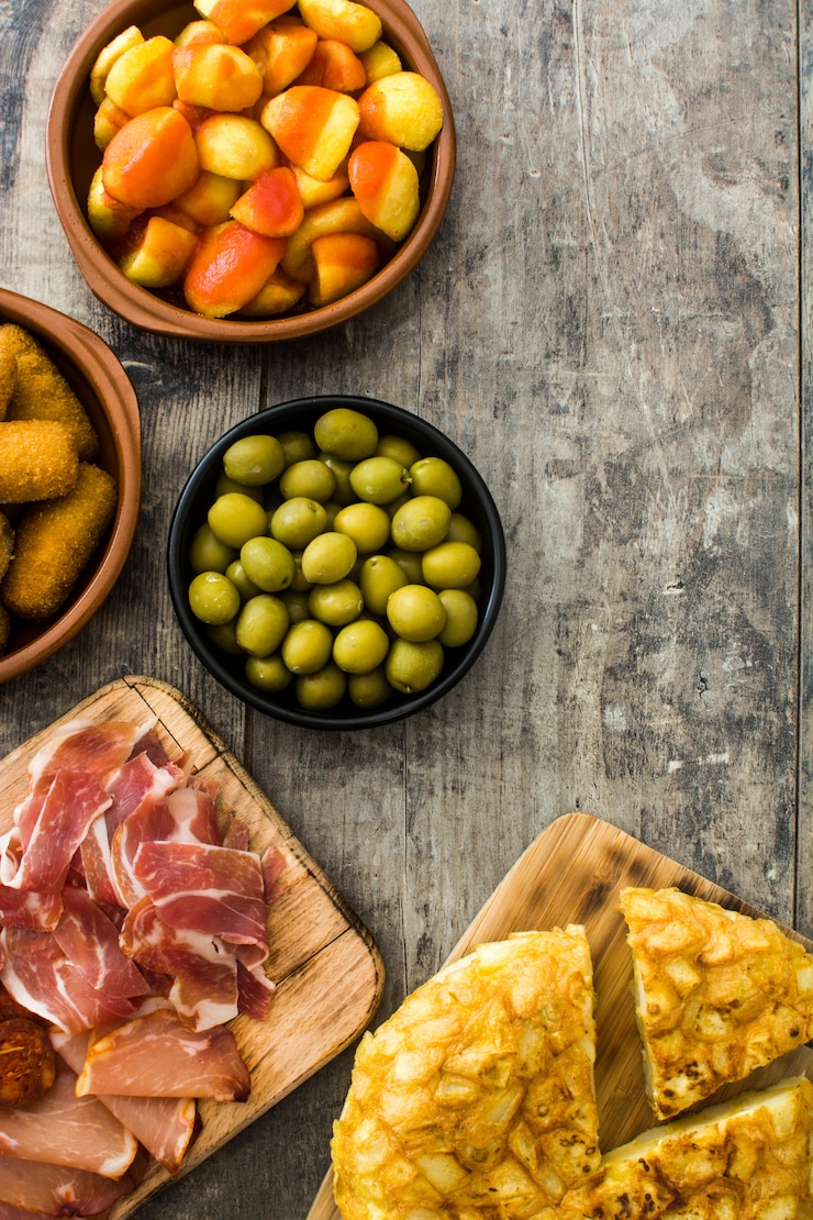 Zdjęcie tradycyjne hiszpańskie tapas. krokiety, oliwki, omlet, szynka i patatas bravas na drewnianym stole