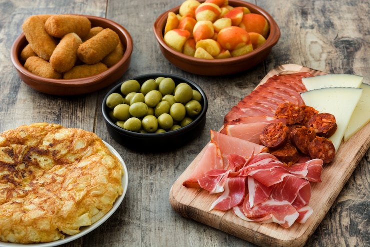 Zdjęcie tradycyjne hiszpańskie tapas krokiety, oliwki, omlet, szynka i patatas bravas na drewnianym stole