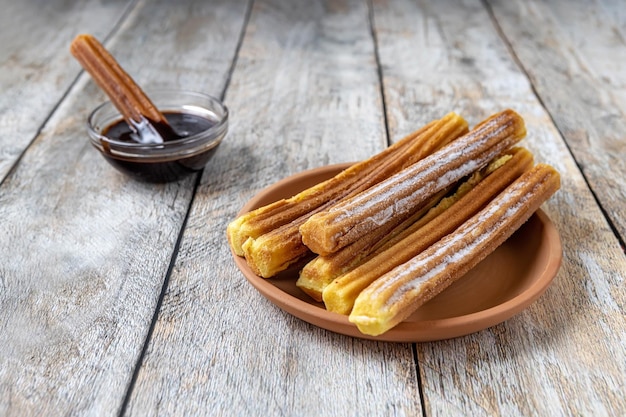 Zdjęcie tradycyjne hiszpańskie wypieki churros i sos czekoladowy na drewnianym tle