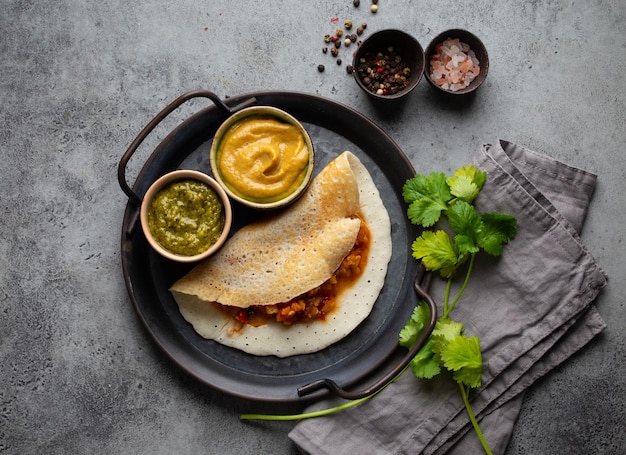 Zdjęcie tradycyjne indyjskie naleśniki ryżowe dosa z warzywami sambar napełnianie dipy chutney na metalowej płytce kamienny tło stół szybki posiłek lub wegetariańska przekąska z południowego indii