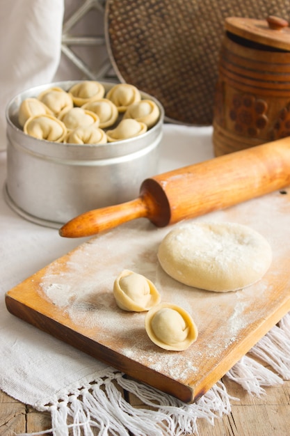 Tradycyjne pelmeni lub pierogi na desce do krojenia. Domowe jedzenie przygotowujące.