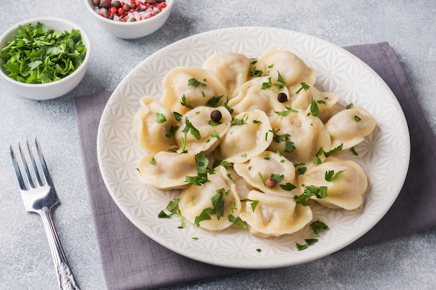 Tradycyjne pelmeni, ravioli, pierogi wypełnione mięsem na talerzu, rosyjska kuchnia.