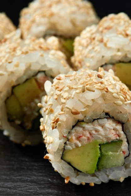 Tradycyjne pyszne świeże rolki sushi ustawione na czarnym tle Rolka sushi z kremem ryżowym serek awokado łosoś sezam Philadelphia Sushi menu Kuchnia japońska restauracja