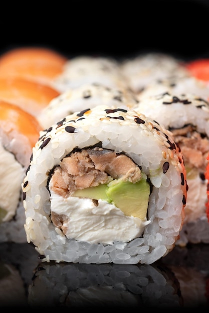 Tradycyjne pyszne świeże rolki sushi ustawione na czarnym tle z odbiciem Sushi menu Japońska kuchnia restauracja