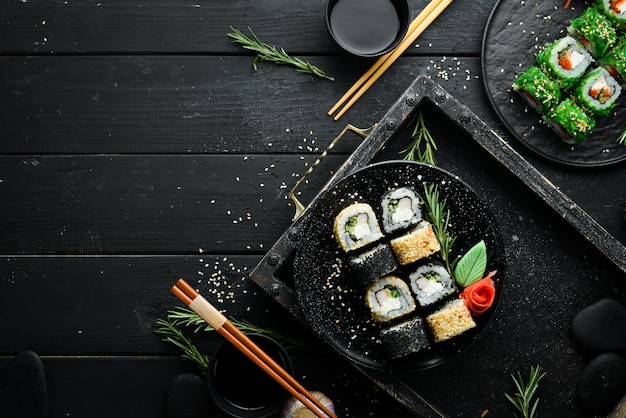 Zdjęcie tradycyjne sushi - czarno-białe z krabem, serem i ziołami. kuchnia japońska. widok z góry.