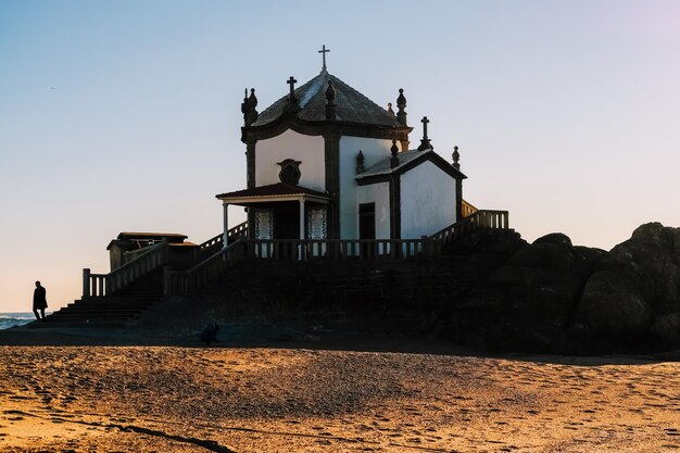 Zdjęcie tradycyjny budynek kościoła nad morzem na tle nieba podczas zachodu słońca - senhor da pedra