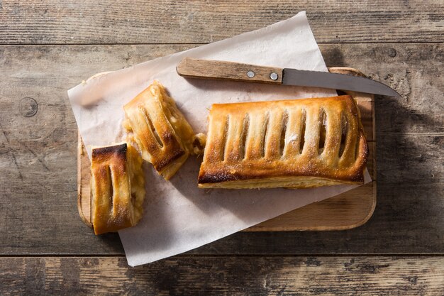 Tradycyjny domowy strudel jabłkowy na drewnianym stole. Widok z góry