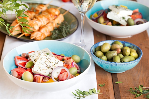 Tradycyjny grecki obiad: sałatka z fetą, souvlaki, oliwkami i winem na dużym stole