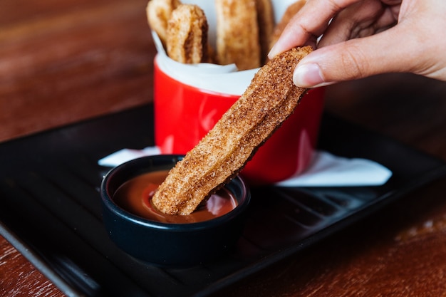 Tradycyjny Hiszpański Deser Churros Z Cukrem I Cynamonem. Zanurzenie W Sosie Czekoladowym.