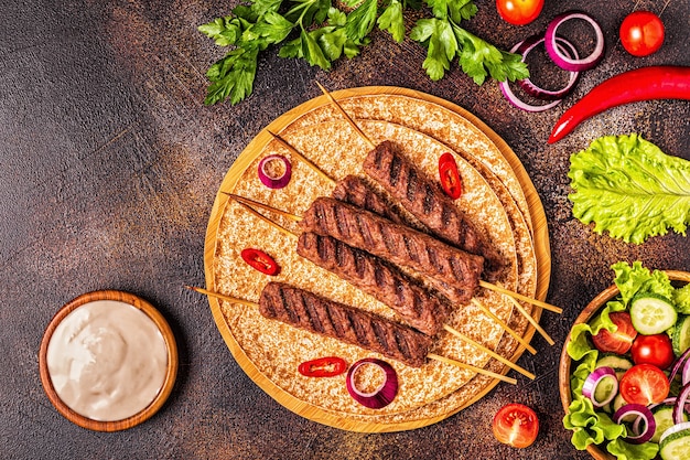 Tradycyjny kebab z mięsa bliskowschodniego, arabskiego lub śródziemnomorskiego z warzywami i chlebem lavash. Widok z góry.