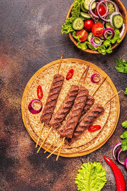 Tradycyjny kebab z mięsa bliskowschodniego, arabskiego lub śródziemnomorskiego z warzywami i chlebem lavash. Widok z góry.