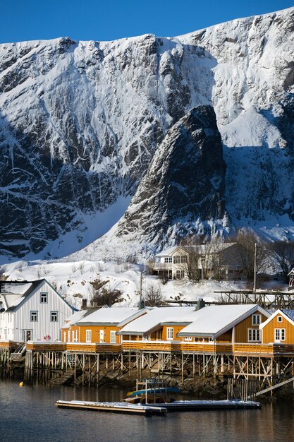 Tradycyjny norweski drewniany dom rorbu do stania na brzegu fiordu i gór w oddali. Lofoty. Norwegia.