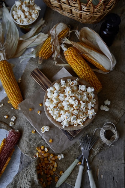 Tradycyjny popcorn w drewnianej misce i kaczany kukurydzy na stole.