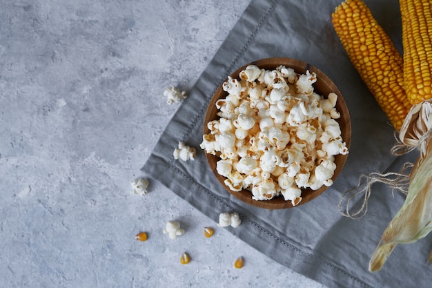 Tradycyjny popcorn w drewnianej misce i kaczany kukurydzy na stole.