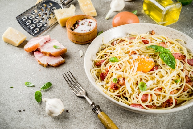 Tradycyjny włoski makaron, spaghetti carbonara z boczkiem, kremowy sos, parmezan, żółtko i świeża bazylia