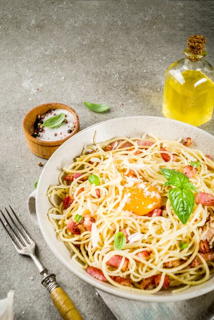 Tradycyjny włoski makaron, spaghetti carbonara z boczkiem, kremowy sos, parmezan, żółtko i świeża bazylia