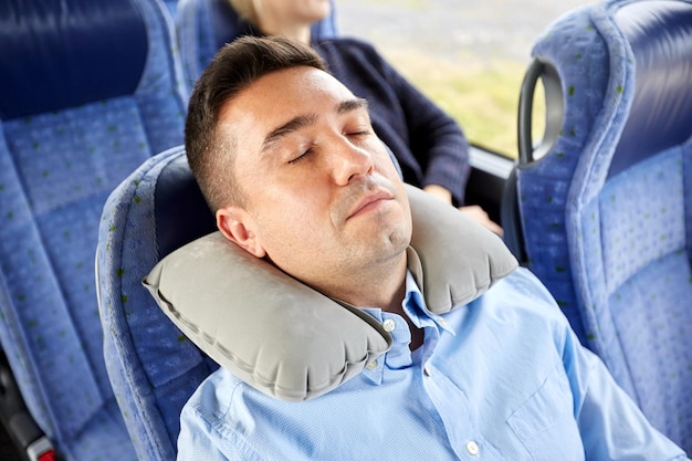 transport, turystyka, odpoczynek, komfort i koncepcja ludzi - mężczyzna śpiący w autobusie lub pociągu z nadmuchiwaną poduszką na szyję