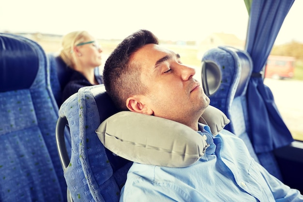 transport, turystyka, odpoczynek, komfort i ludzie koncepcja - mężczyzna śpiący w autobusie podróżującym z nadmuchiwaną poduszką na szyję macicy