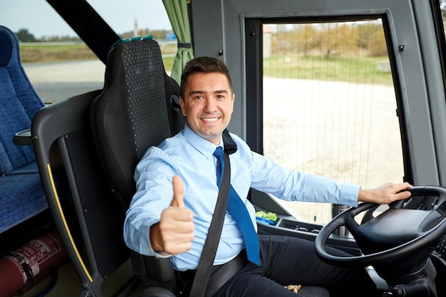 transport, turystyka, wycieczka samochodowa i koncepcja ludzi - szczęśliwy kierowca jadący autobusem międzymiastowym i śnieżne kciuki do góry