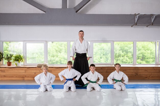 Trener Blisko Uczniów. Młody, Ale Doświadczony Trener Aikido Stojący W Pobliżu Swoich Małych Uczniów