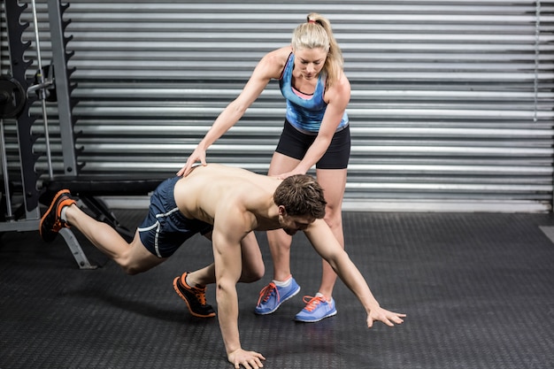 Trener kobieta pomaga mężczyzna na siłowni crossfit