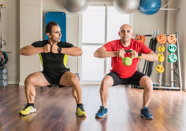 Trener Personalny Obok Mężczyzny ćwiczącego Z Kettlebell Na Siłowni