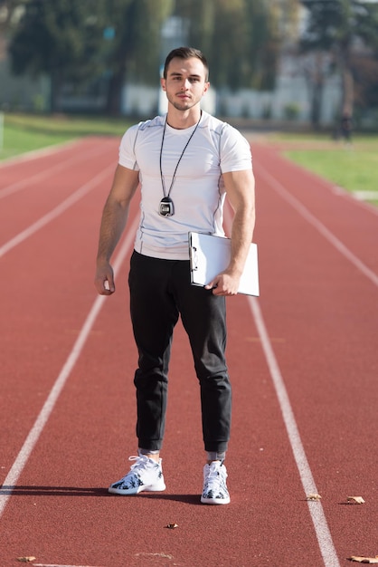 Trener personalny w stroju sportowym robi notatki w schowku w parku miejskim Trening i ćwiczenia wytrzymałościowe Koncepcja zdrowego stylu życia Outdoor