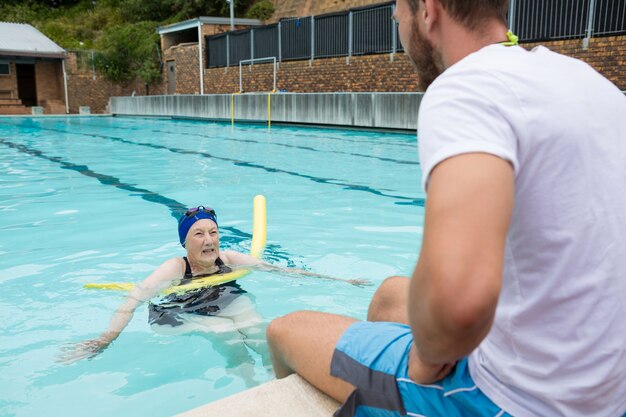 Trener pływania w interakcji z starszą kobietą przy basenie